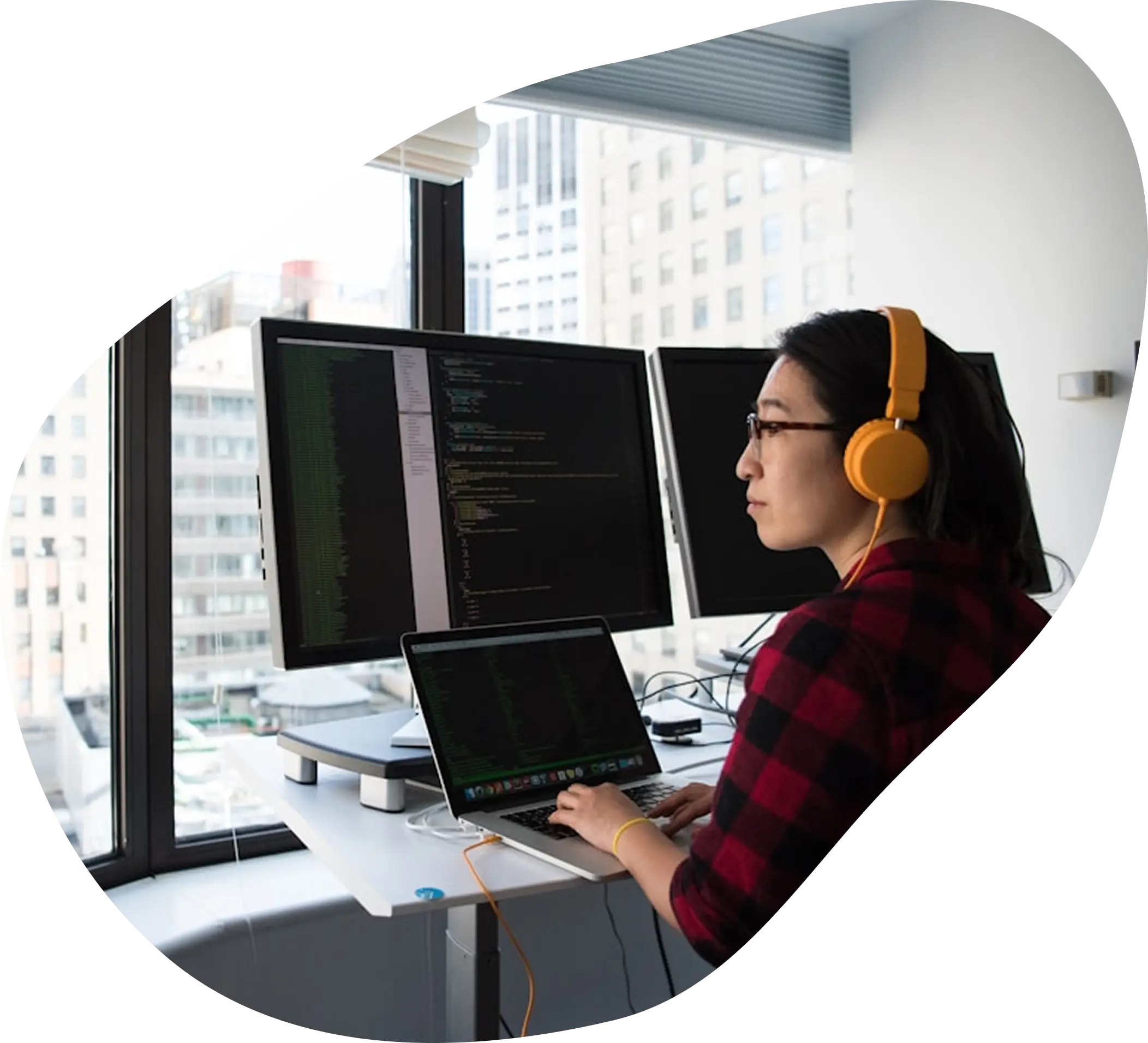 An IT team member wearing headphones, working across several monitors at a service desk